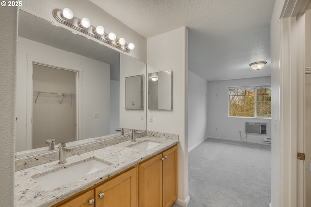 bathroom featuring a textured ceiling, vanity, and a wall unit AC