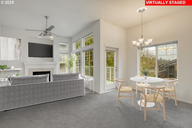 interior space featuring ceiling fan with notable chandelier and a tile fireplace