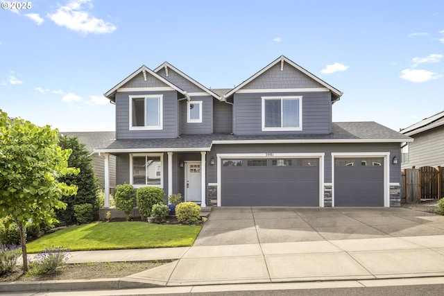 3981 N Boomer Dr, Newberg, OR 97132 - view of front facade featuring driveway, roof with shingles, an attached garage, stone siding, and covered porch