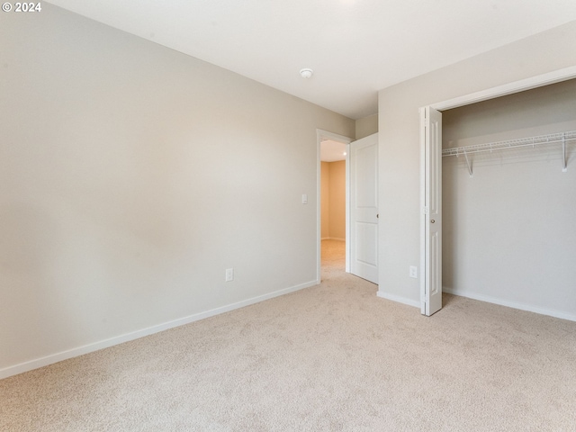 unfurnished bedroom featuring a closet and light colored carpet