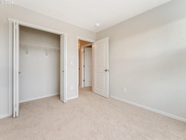 unfurnished bedroom featuring light carpet and a closet