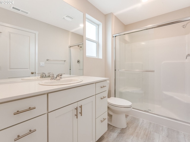 bathroom with wood-type flooring, toilet, a shower with door, and vanity