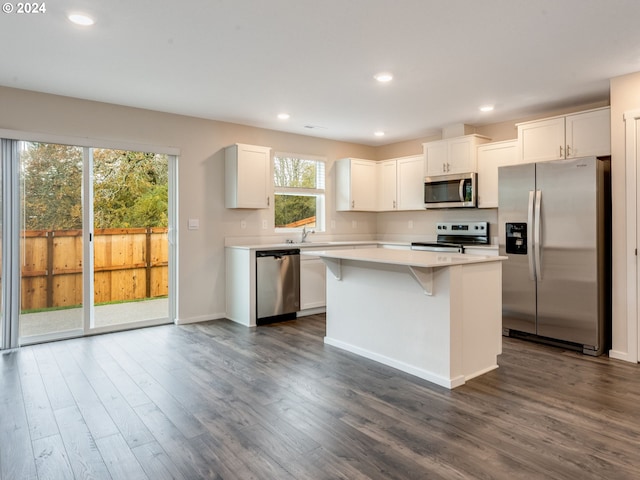 kitchen featuring dark hardwood / wood-style floors, appliances with stainless steel finishes, white cabinets, and a kitchen island