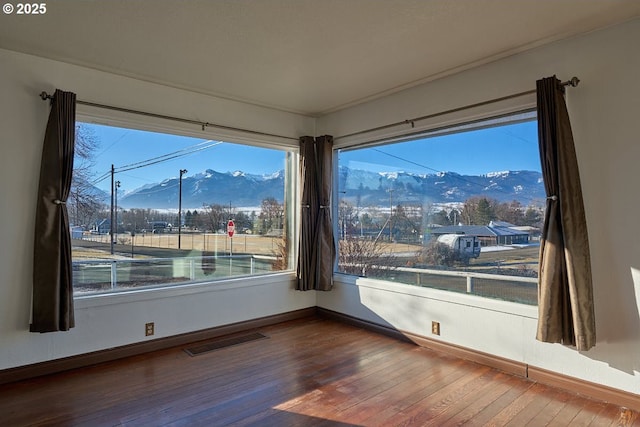 unfurnished room with hardwood / wood-style flooring and a mountain view