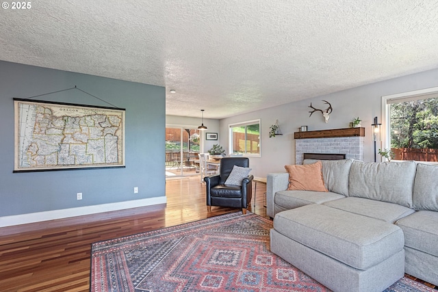 406 Balsa St, La Grande, OR 97850 - living room featuring wood finished floors, a textured ceiling, a brick fireplace, and baseboards