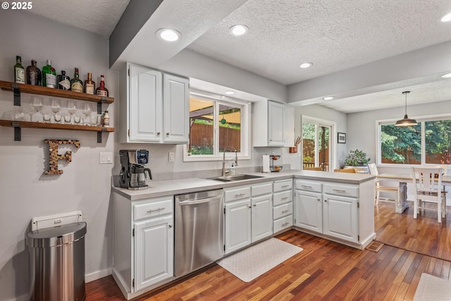 406 Balsa St, La Grande, OR 97850 - kitchen featuring dishwasher, a sink, a peninsula, wood finished floors, and a textured ceiling
