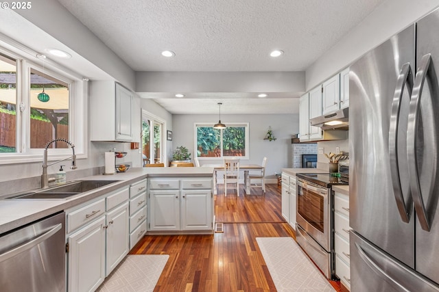 406 Balsa St, La Grande, OR 97850 - kitchen featuring stainless steel appliances, under cabinet range hood, a sink, a peninsula, and white cabinets