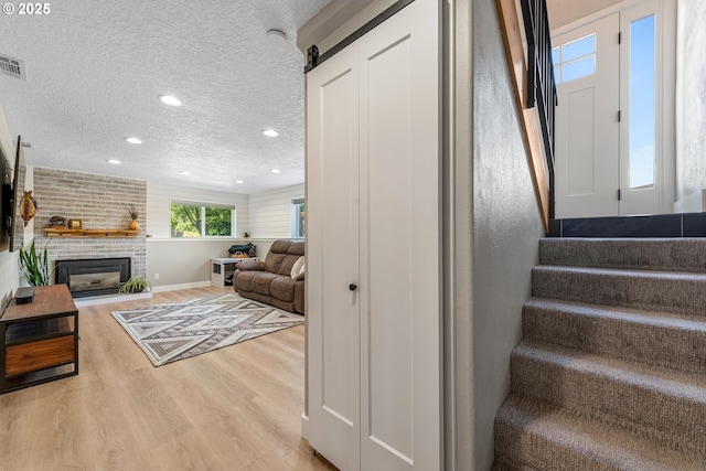 406 Balsa St, La Grande, OR 97850 - staircase with wood finished floors, a textured ceiling, recessed lighting, a brick fireplace, and baseboards