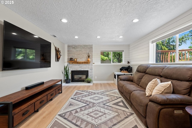 406 Balsa St, La Grande, OR 97850 - living area featuring a textured ceiling, light wood-type flooring, a fireplace, recessed lighting, and baseboards