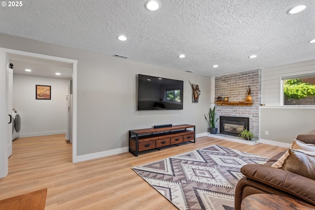 406 Balsa St, La Grande, OR 97850 - living room featuring a textured ceiling, light wood-style flooring, separate washer and dryer, recessed lighting, and a fireplace