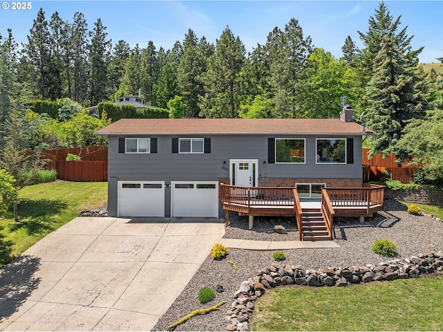 406 Balsa St, La Grande, OR 97850 - bi-level home with a deck, a chimney, concrete driveway, a garage, and a view of trees