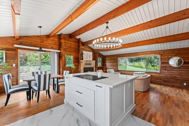 kitchen with open floor plan, vaulted ceiling with beams, white cabinetry, black electric stovetop, and wooden walls