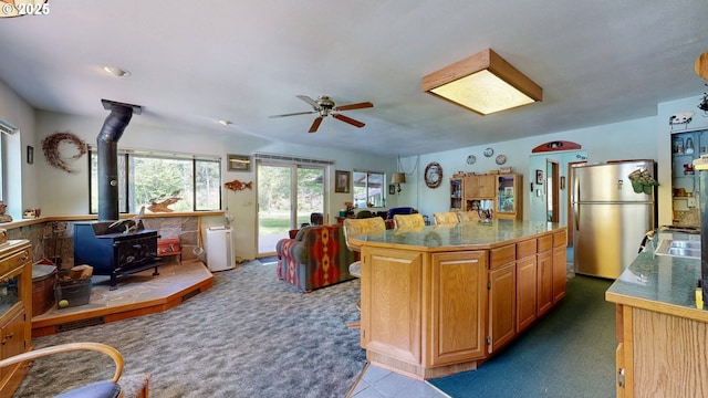 84932 Straw Springs Ln, Milton-Freewater, OR 97862 - kitchen featuring freestanding refrigerator, a wood stove, ceiling fan, dark carpet, and open floor plan