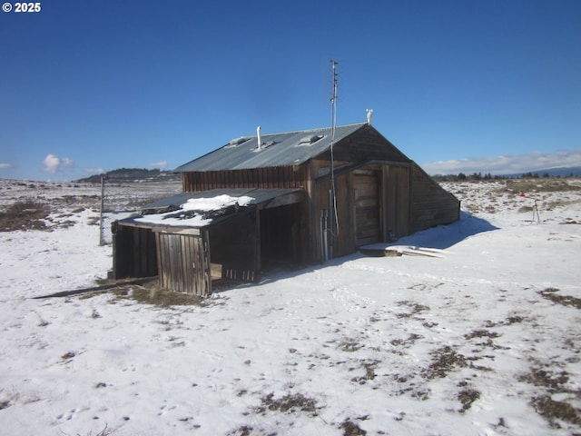 snow covered structure with an outbuilding