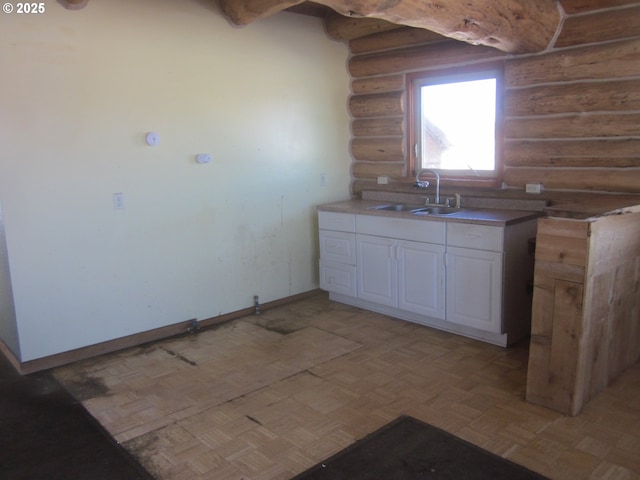 kitchen featuring baseboards, white cabinets, light countertops, open shelves, and a sink