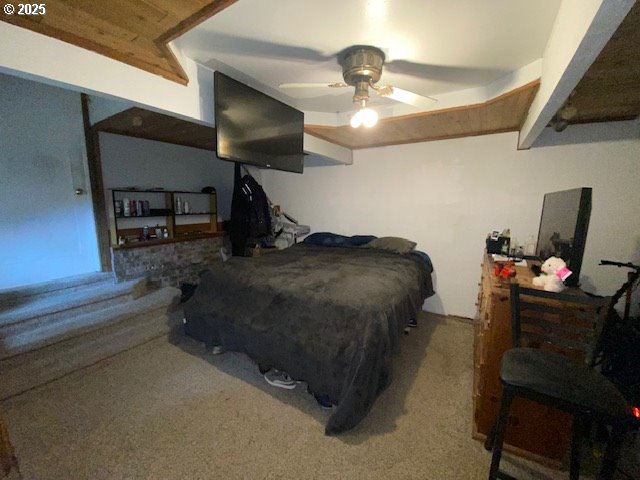 carpeted bedroom featuring beamed ceiling and ceiling fan