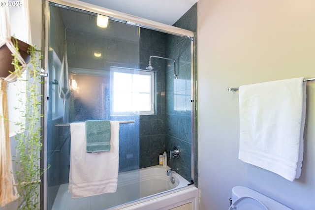 bathroom with combined bath / shower with glass door and toilet