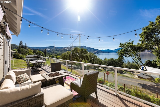 wooden deck with a water and mountain view and an outdoor living space with a fire pit