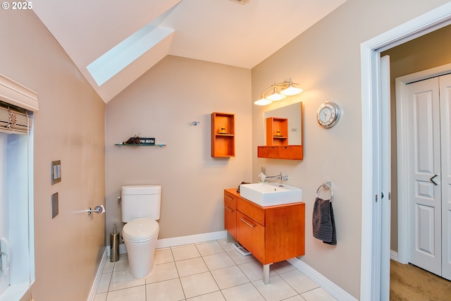 bathroom with vanity, toilet, tile patterned flooring, and lofted ceiling with skylight