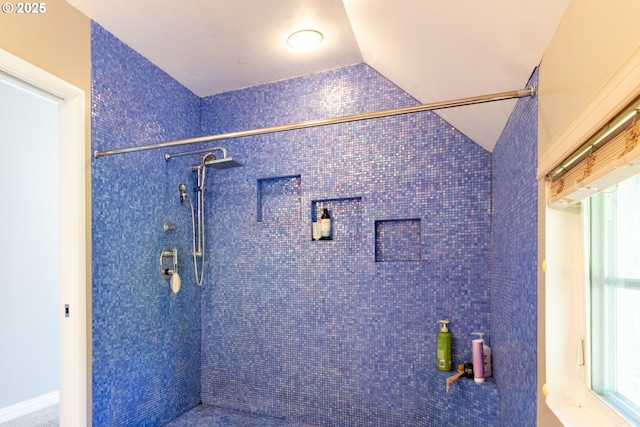 bathroom featuring vaulted ceiling and a tile shower