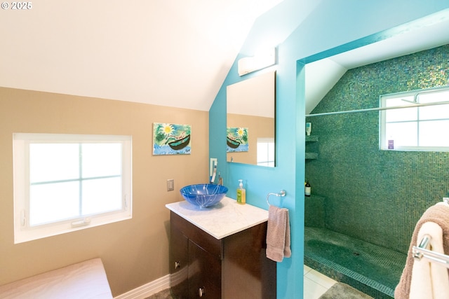 bathroom with vanity, lofted ceiling, tiled shower, and tile patterned floors