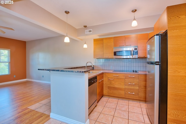 kitchen with appliances with stainless steel finishes, sink, pendant lighting, and kitchen peninsula