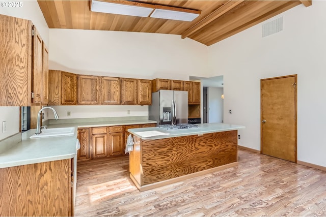 17708 SW Meadowbrook Way, Beaverton, OR 97078 - kitchen featuring stainless steel refrigerator with ice dispenser, a sink, light countertops, a kitchen island, and brown cabinetry