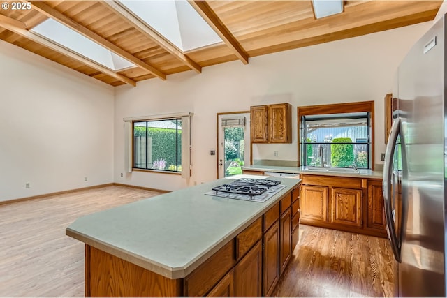 17708 SW Meadowbrook Way, Beaverton, OR 97078 - kitchen with freestanding refrigerator, a skylight, brown cabinetry, wooden ceiling with exposed beams, and light wood finished floors