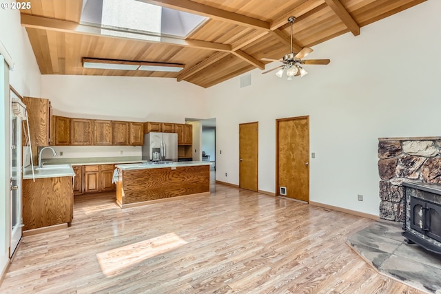 17708 SW Meadowbrook Way, Beaverton, OR 97078 - kitchen featuring a wood stove, stainless steel refrigerator with ice dispenser, brown cabinets, a sink, and light countertops