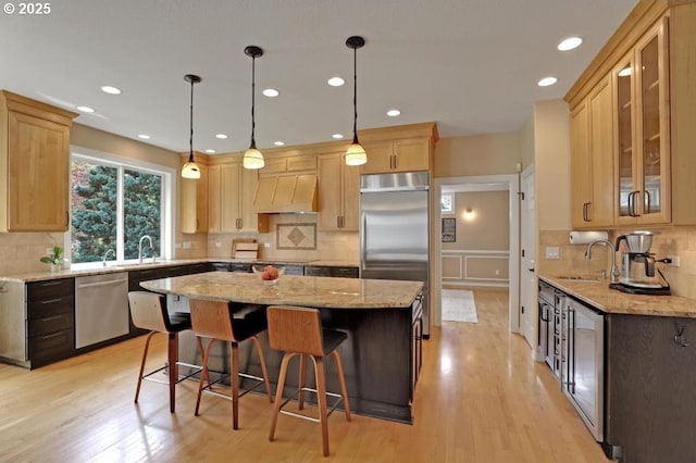 kitchen with appliances with stainless steel finishes, backsplash, a kitchen island, and extractor fan