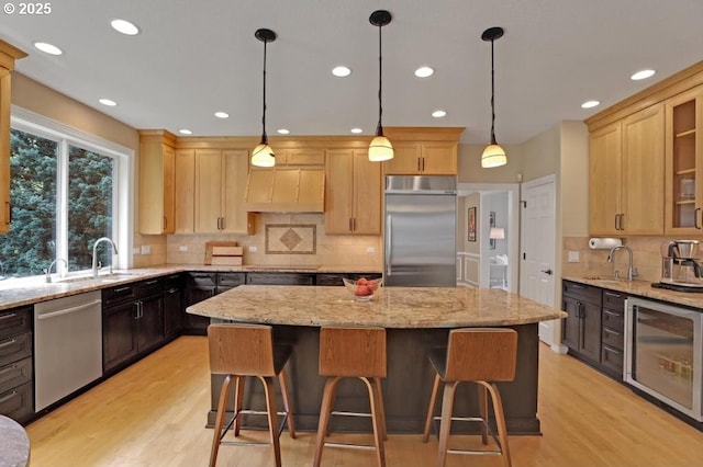 kitchen featuring beverage cooler, appliances with stainless steel finishes, a sink, and a center island