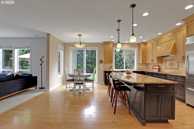 kitchen featuring plenty of natural light, custom range hood, and light wood-style floors