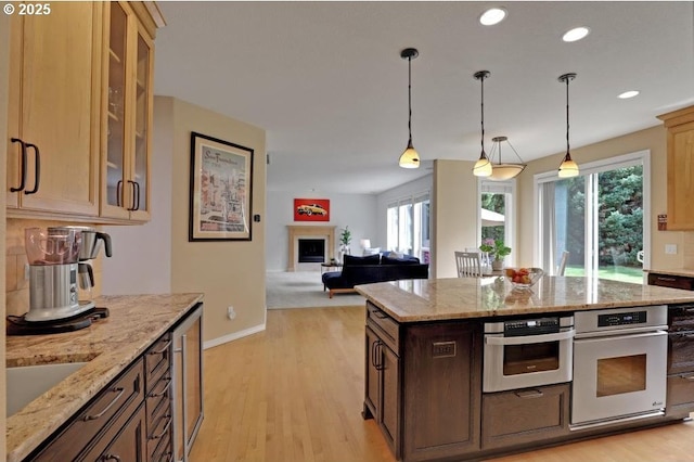 kitchen with oven, light wood-style flooring, recessed lighting, pendant lighting, and glass insert cabinets