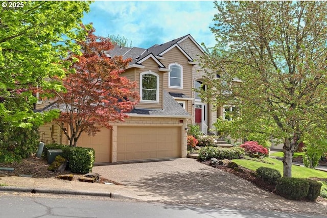 traditional home with a garage, a shingled roof, and concrete driveway