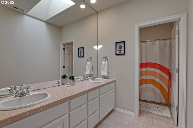 full bath with double vanity, visible vents, a sink, and tile patterned flooring