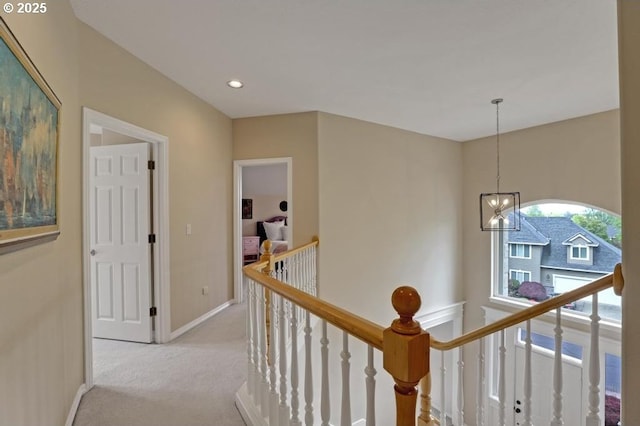 corridor with an inviting chandelier, light carpet, baseboards, recessed lighting, and an upstairs landing