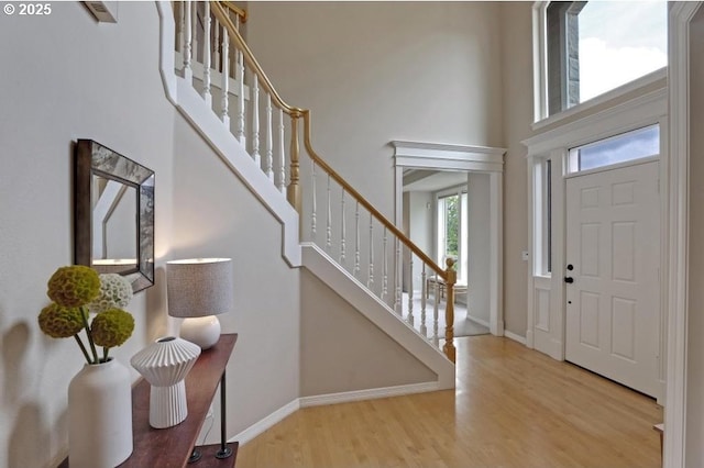 entryway with baseboards, a high ceiling, stairs, and wood finished floors