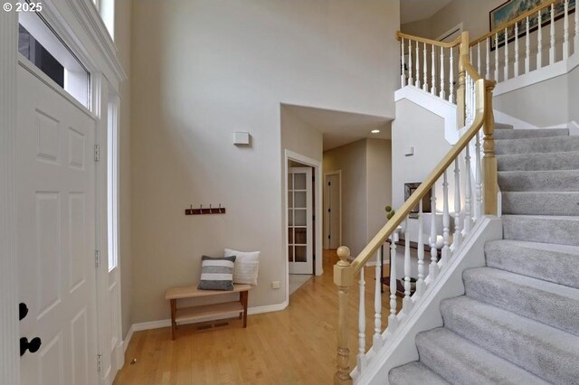 foyer featuring wood finished floors, baseboards, a high ceiling, stairs, and a wealth of natural light