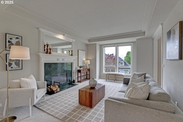 living room with a high end fireplace, a raised ceiling, and carpet flooring