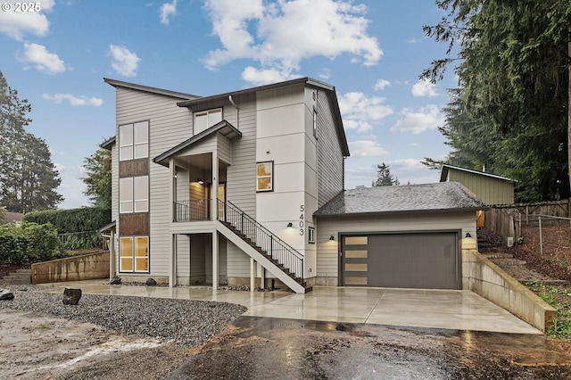 contemporary house featuring aphalt driveway, stairway, an attached garage, and fence