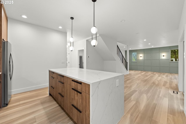 kitchen featuring modern cabinets, stainless steel fridge with ice dispenser, light wood-style floors, and a center island