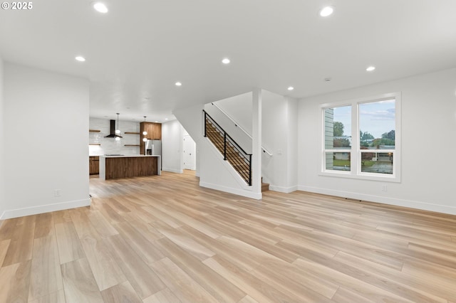 unfurnished living room featuring stairs, recessed lighting, and light wood-style floors