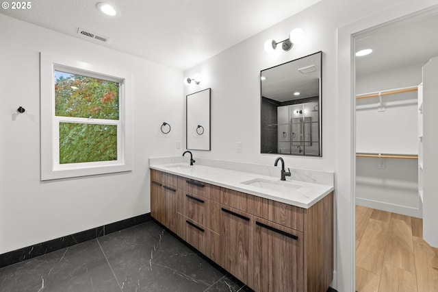 full bath with a sink, visible vents, baseboards, and double vanity