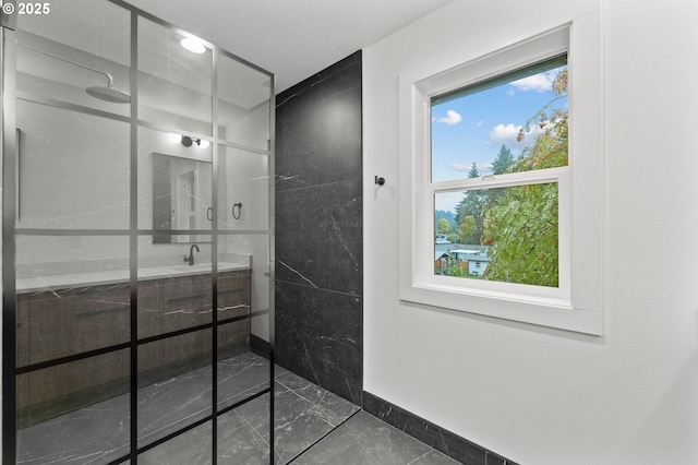 full bath with marble finish floor, a sink, a textured ceiling, baseboards, and walk in shower