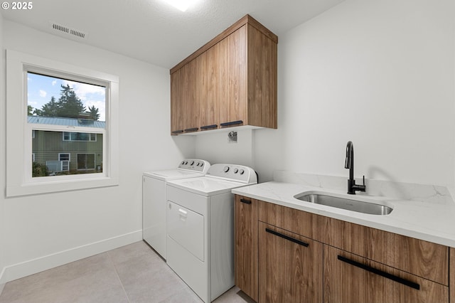 laundry area with visible vents, a sink, washing machine and dryer, cabinet space, and baseboards