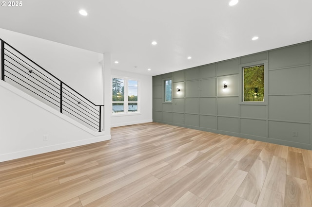 unfurnished living room with recessed lighting, stairs, and light wood-style floors