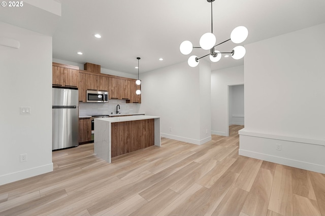 kitchen featuring brown cabinetry, a kitchen island, light countertops, appliances with stainless steel finishes, and backsplash