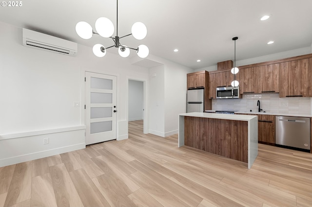 kitchen featuring brown cabinetry, a sink, a wall mounted air conditioner, appliances with stainless steel finishes, and tasteful backsplash