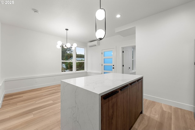 kitchen with pendant lighting, baseboards, light wood-style floors, and an AC wall unit