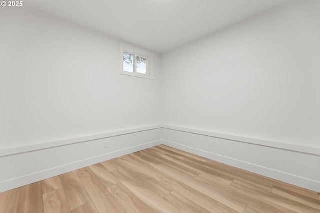 spare room with baseboards and light wood-type flooring